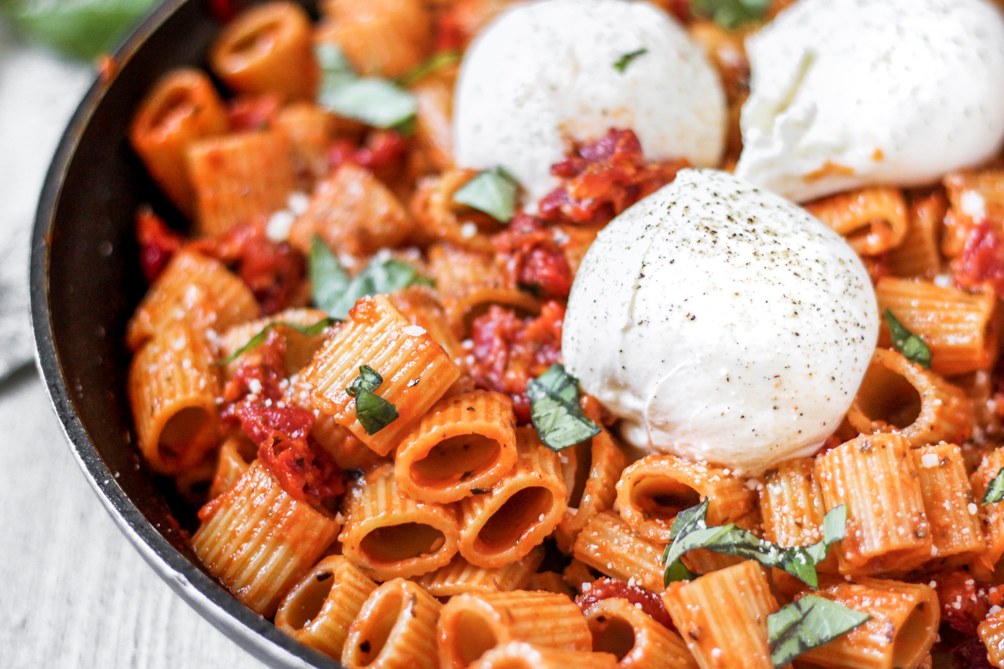 close shot of the rigatoni pasta with 3 balls of burrata cheese.