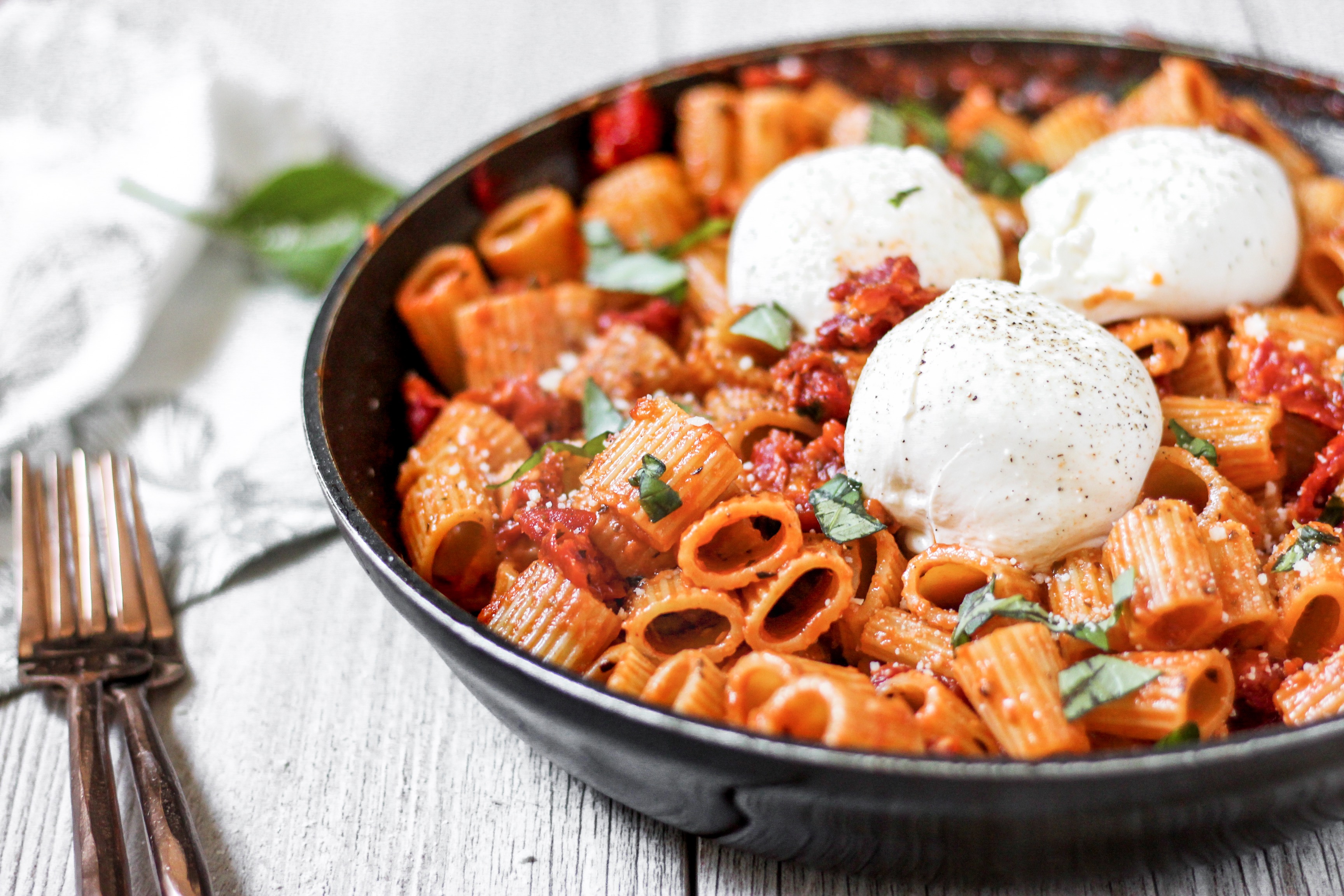 pasta in the pan with 3 balls of Burrata and 2 forks.