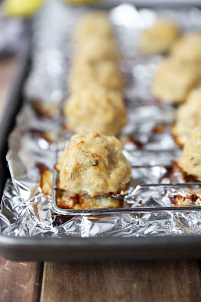 baked chicken meatballs on a baking rack on a foil-lined baking sheet.