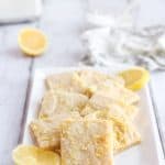 A white rectangular plate with lemon sugar cookies squares.