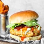 buffalo chicken burger on wood board with sweet potato fries