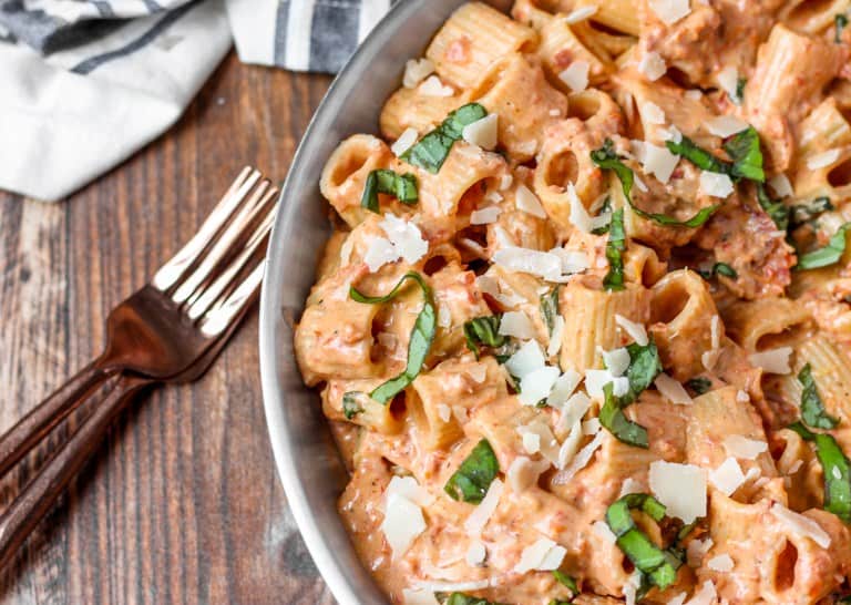 overhead shot of the pasta in a stainless steel pan with two forks on a wood surface.