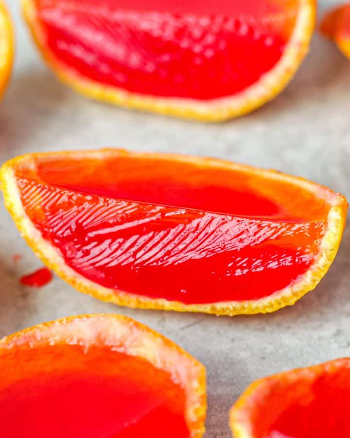 Group of the orange slice jello shots on a light grey board.