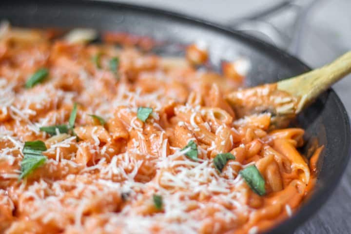 penne vodka in a pan with a wood spoon.