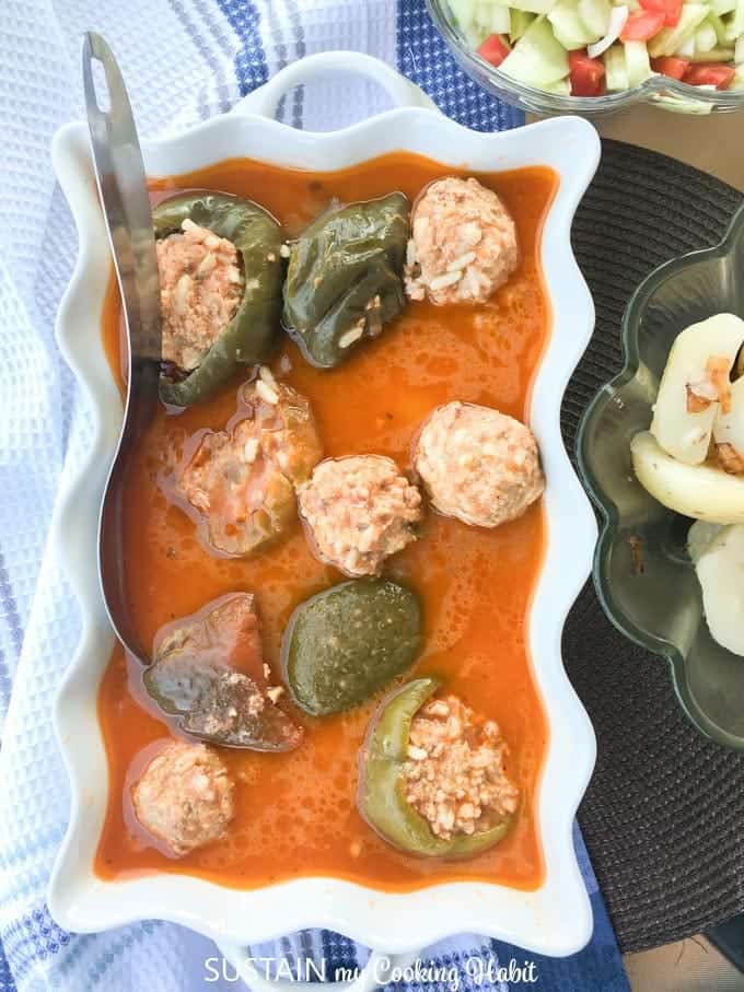 overhead shot of the stuffed peppers in sauce in a white casserole dish.