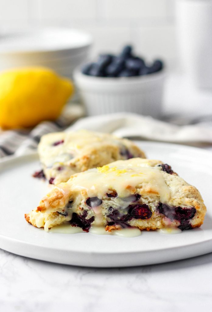 two lemon blueberry scones on a white round plate.