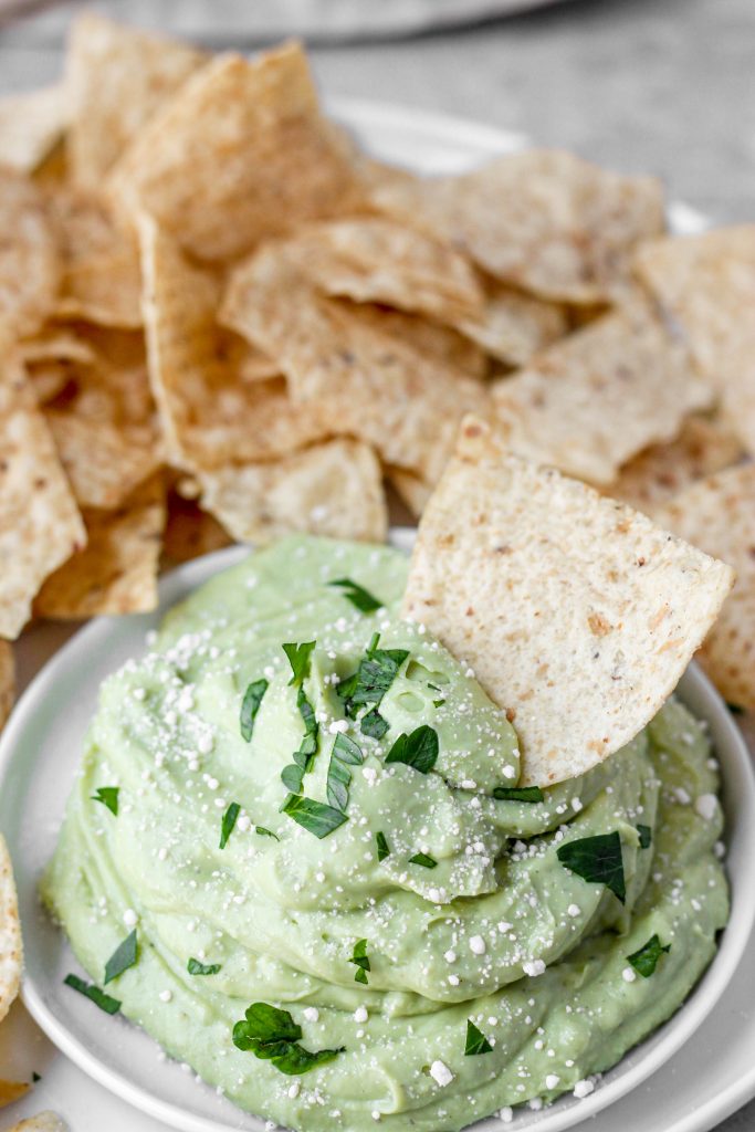 whipped avocado butter fruit on a white plate with chips.