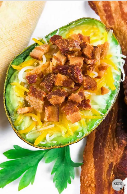 overhead shot of an egg stuffed avocado with cheese and bacon.