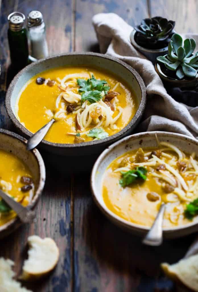 pumpkin soup in bowls on a dark wood surface