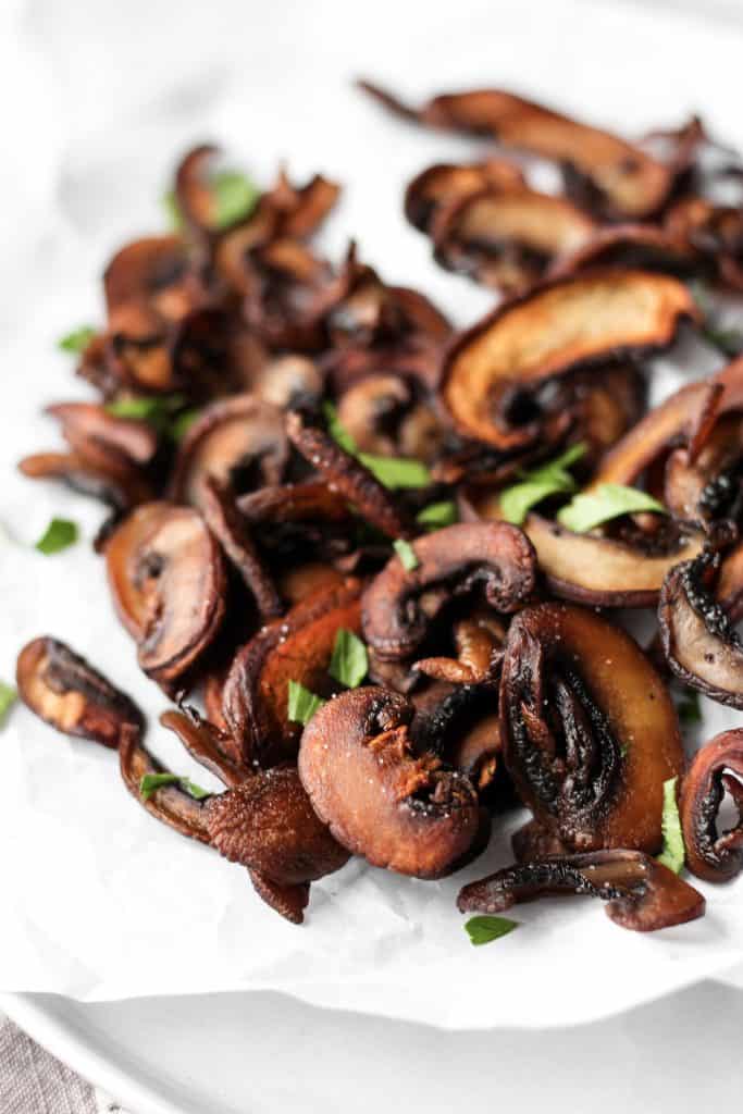 close shot of mushroom chips on a plate with parsley. 