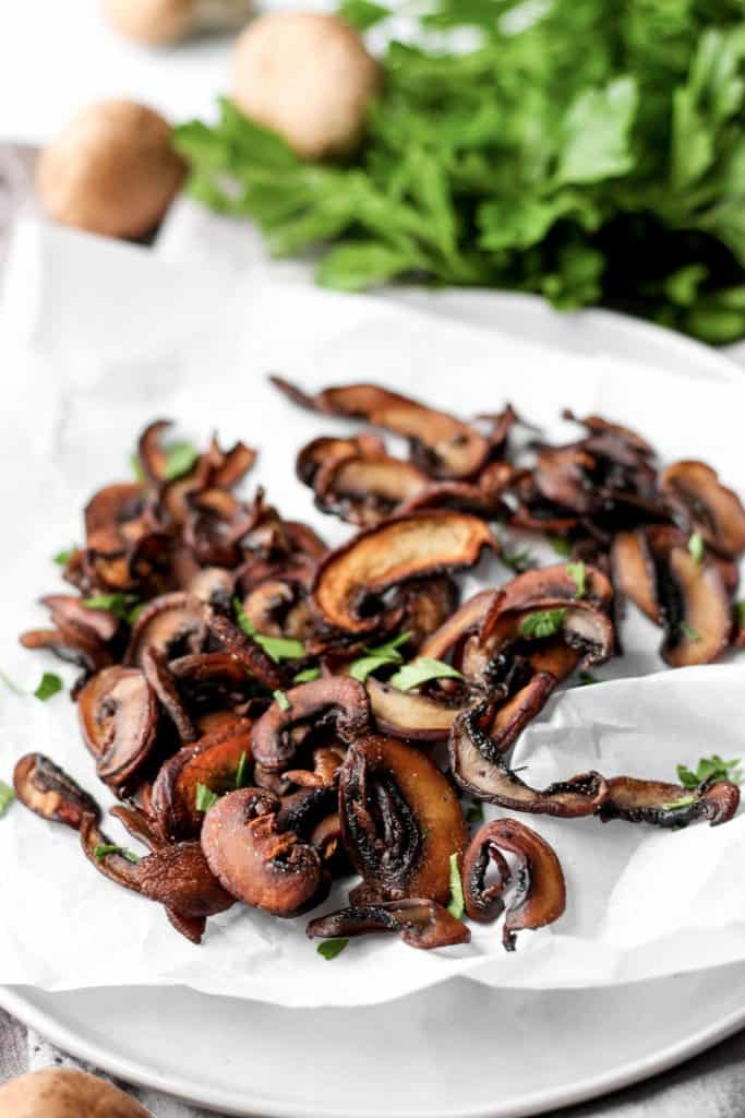 mushroom chips on a white plate with parsley. 