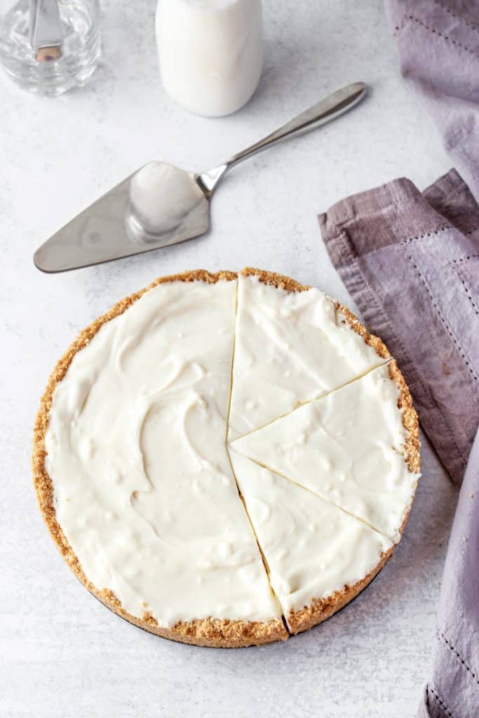 overhead shot of the no bake coconut cheesecake with a pie server and a napkin on a cement surface.