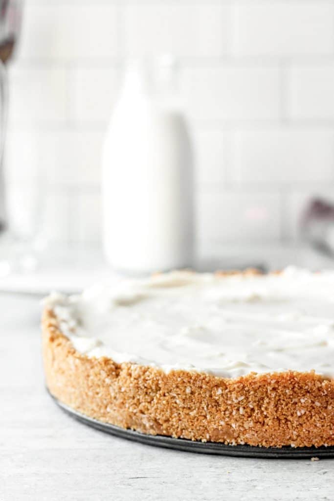 Side view close to the crust, a glass of milk in the background.