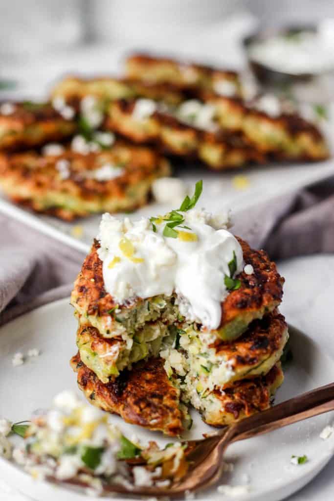 stack of 3 fritters with a section cut out and a fork with some fritter on it in the foreground.