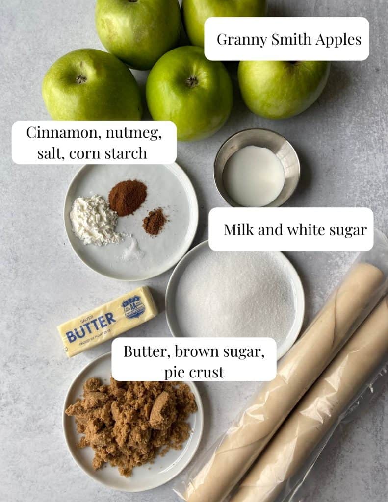 image of the ingredients, butter, brown and white sugar, salt, corn starch, spices, dough, apples, and milk.