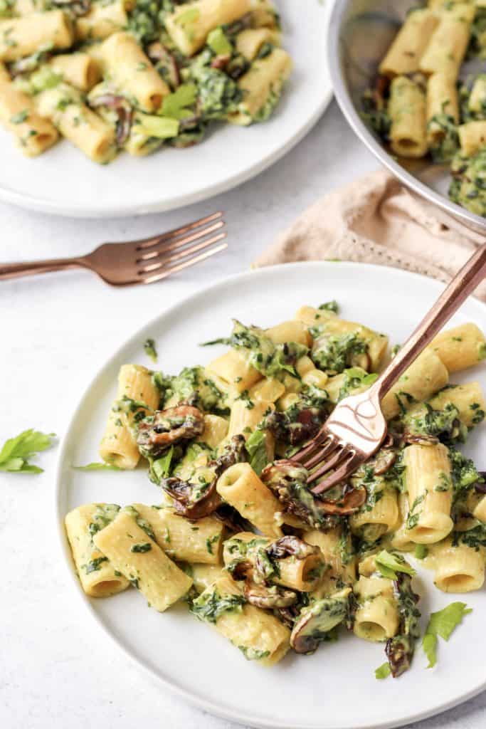 a fork digging into the pasta on a round white plate.