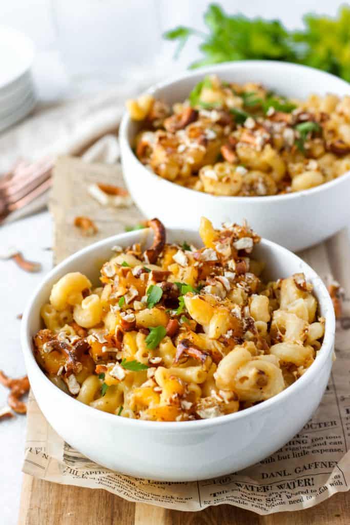 beer cheese mac and cheese in a bowl on a wood board, parsley in the background.