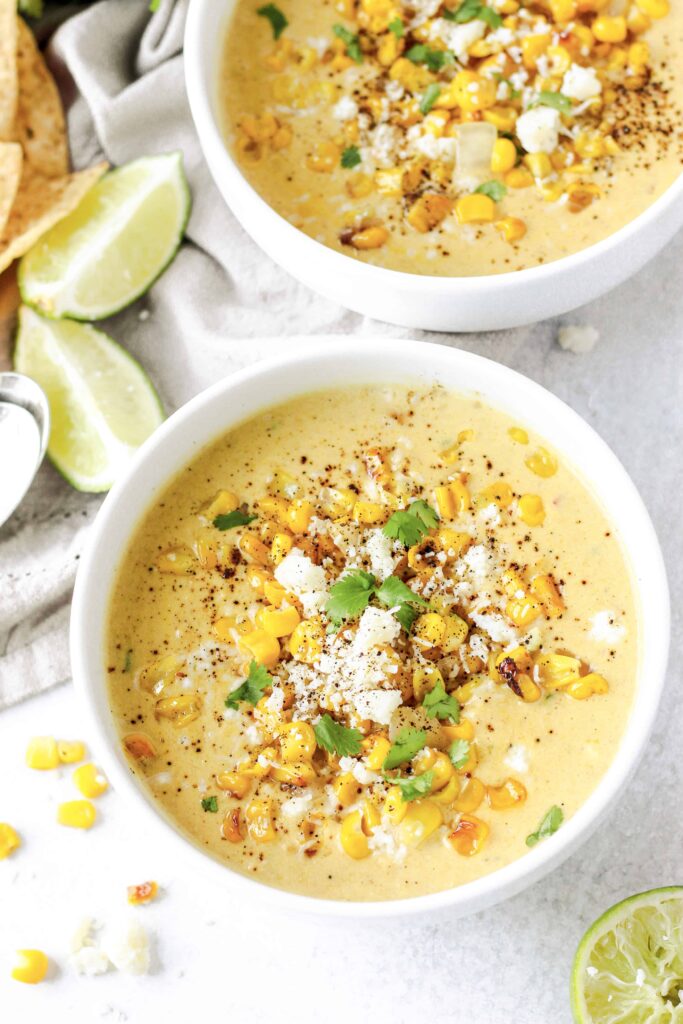 overhead shot of the corn chowder in a round white bowl with some corn scattered.