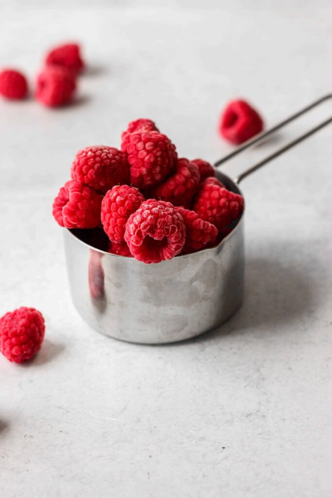 frozen fresh raspberries in a silver measuring cup.