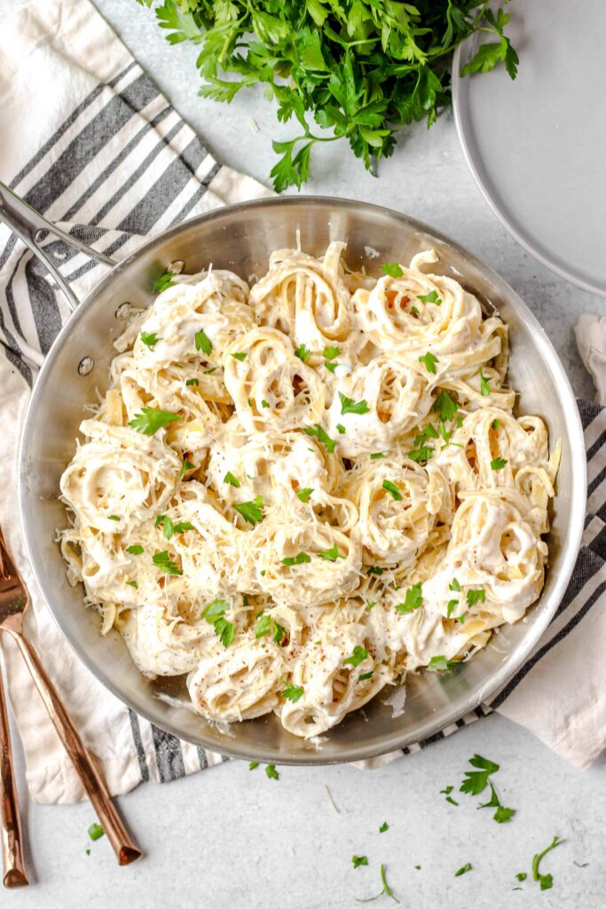 overhead shot of a silver pan with spiraled noodles of fettuccine Alfredo