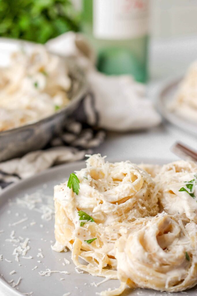 close photo of a mound of spiraled noodles in Alfredo sauce.