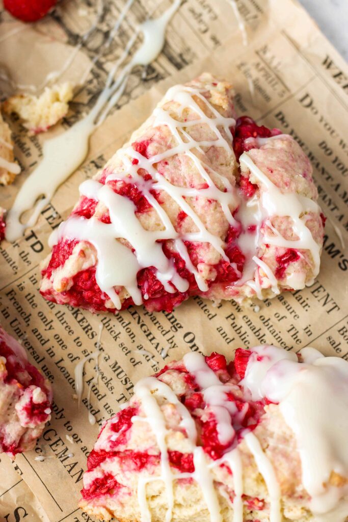 close shot of one scone on the beige newsprint food paper.