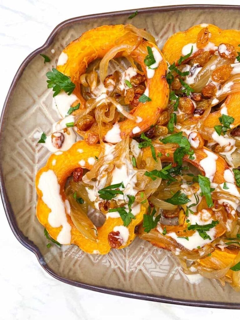 overhead shot of delicata squash, sliced, with a tahini dressing.