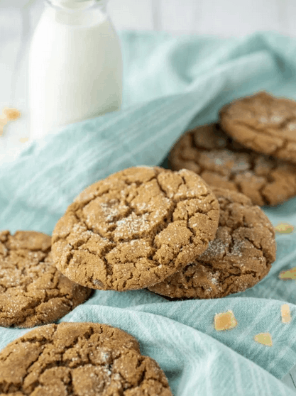 molasses cookies on a blue linen with pieces of fresh ginger