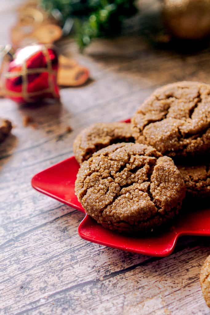 gingersnaps on a red plate with ornaments in the background.