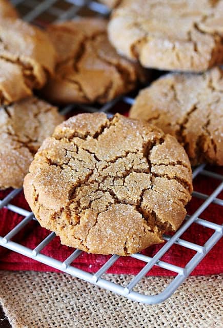 molasses cookie on a cooling rack on red and beige linens.