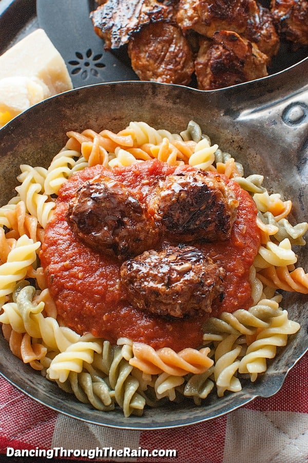 baked chicken meatballs on a plate of rotini pasta with red sauce.