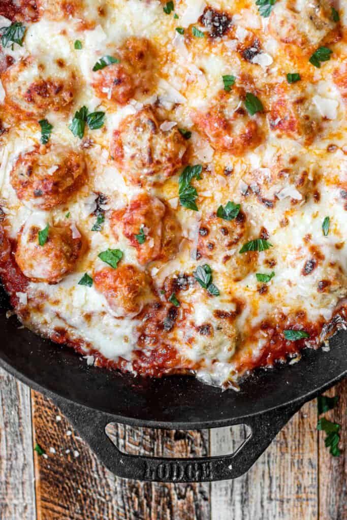 overhead shot of chicken parm meatballs in a cast iron skillet.