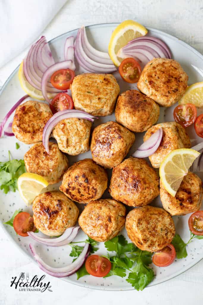 overhead shot of the chicken kofta with onions, lemons, and tomatoes.