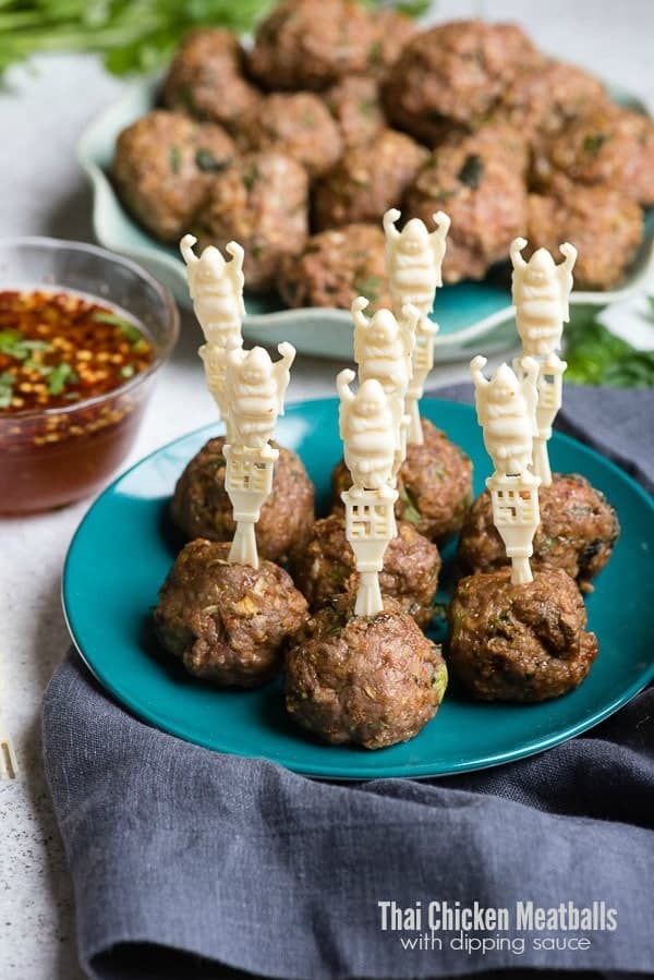 Thai chicken meatballs with toothpicks on a teal plate and a navy napkin.