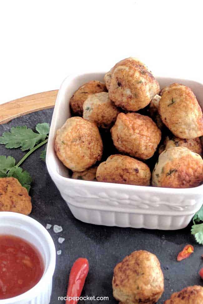 chicken meatballs in a white container with a sweet chili sauce.