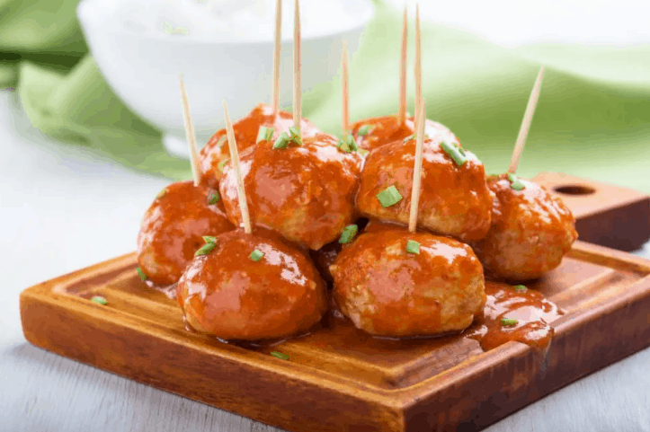 Jamaican jerk meatballs with toothpicks on a wood board.