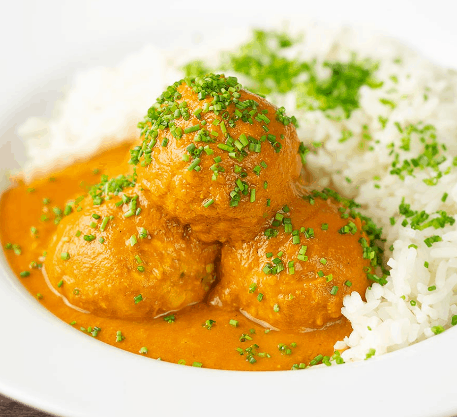 a pile of the chicken kofta masala topped with chives and rice in the background.