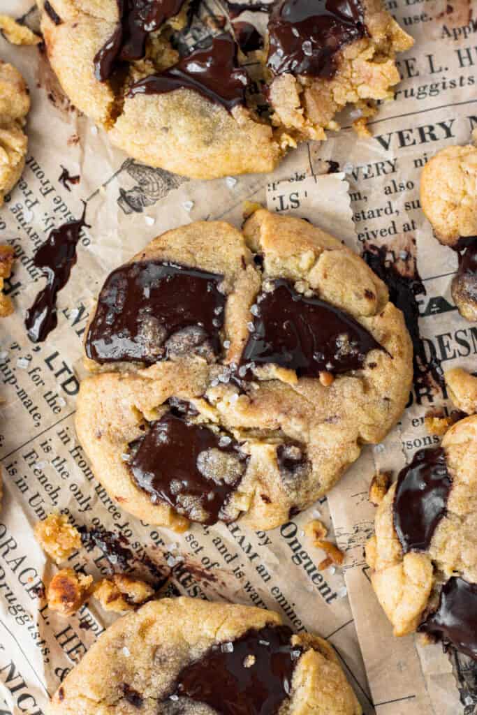 close overhear shot of the cookies with large pools of melted chocolate and sprinkled sea salt  on brown newsprint paper.