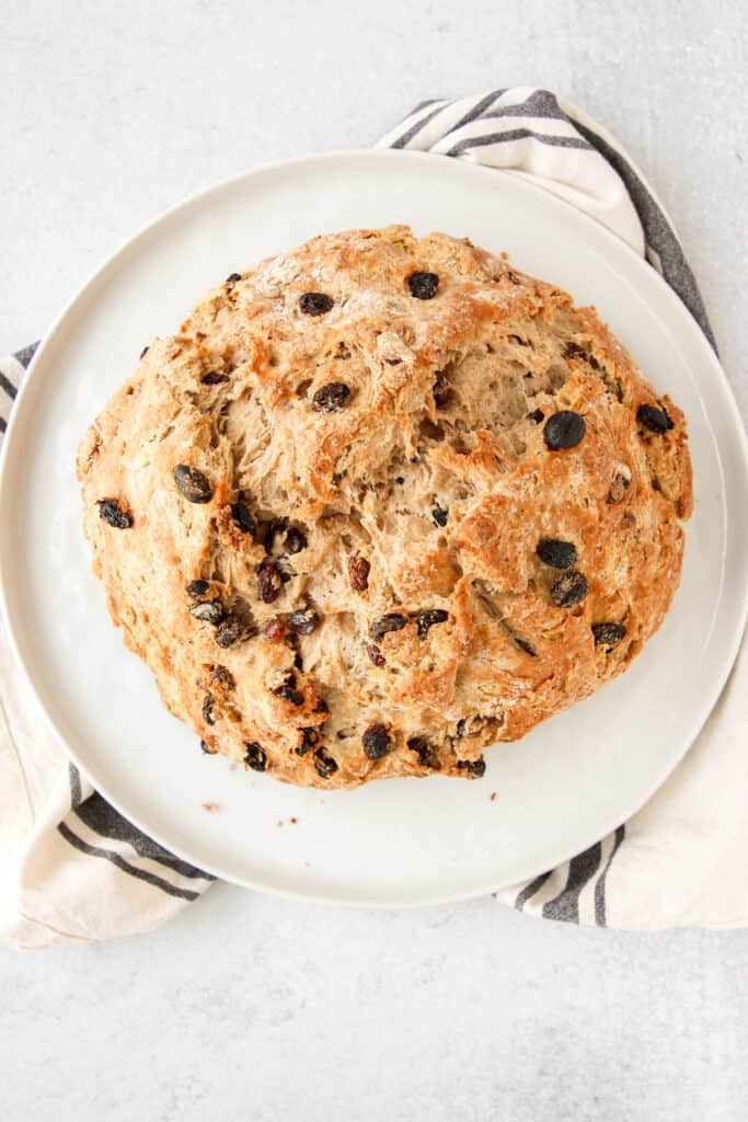 overhead shot of the cinnamon raisin soda bread on a white round plate.