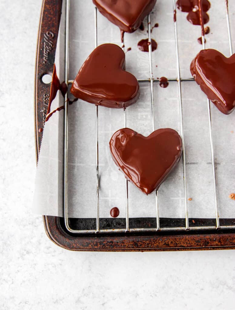 overhead shot of the heart shaped cookie dough bites covered in chocolate on the baking sheet.