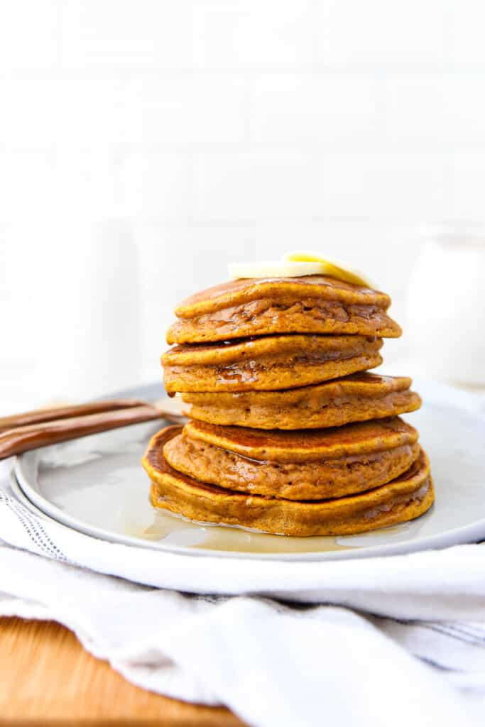 stack of 5 pumpkin pancakes with butter on top.