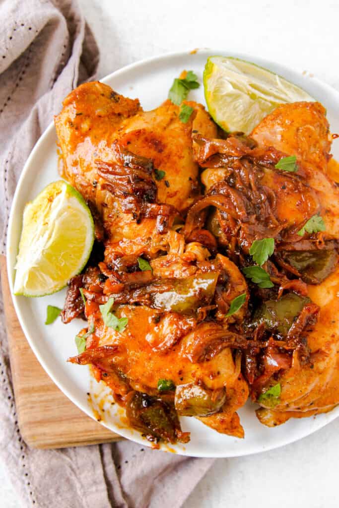 overhead shot of the finished cooked chicken topped the peppers and onions and a wedge of lime.