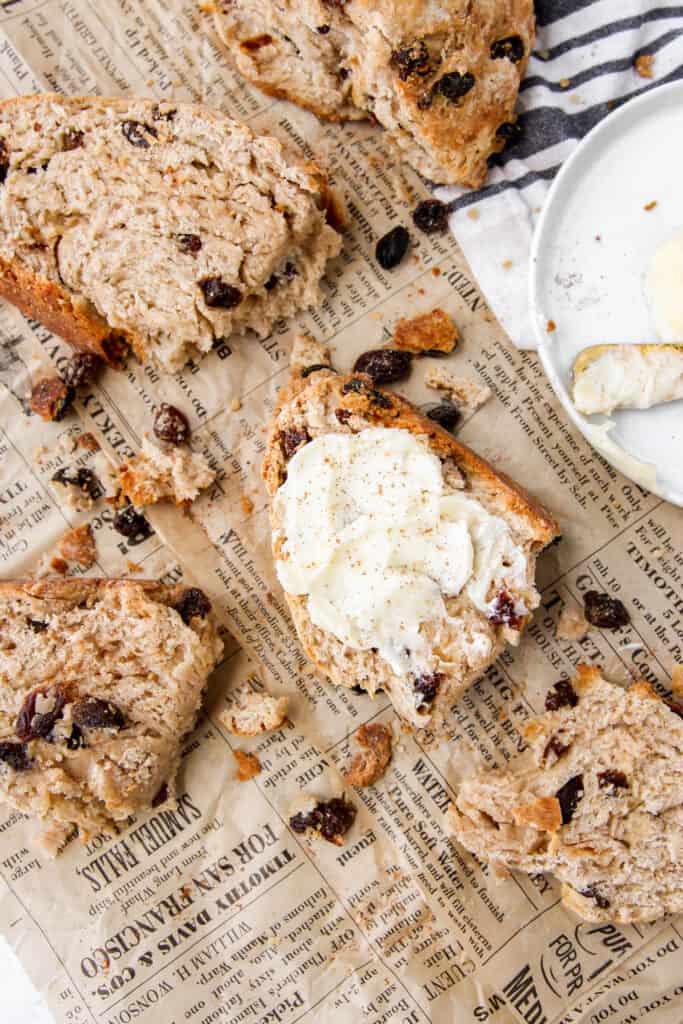 overhead shot of a slice of cinnamon raisin soda bread with butter on brown newsprint paper