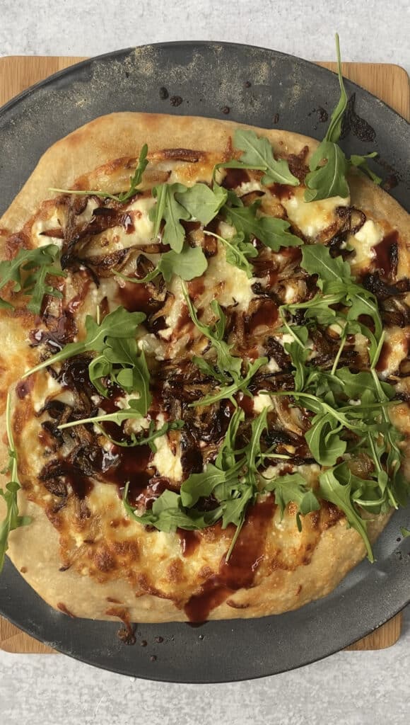 overhead shot of the finished pizza topped with the arugula and the raspberry balsamic vinegar.