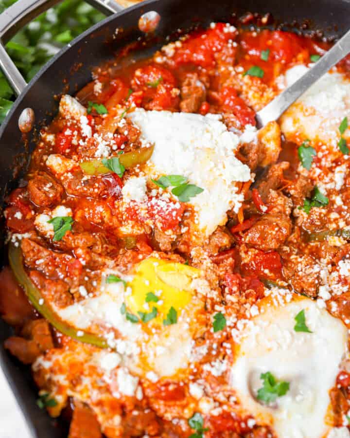chorizo shakshuka in a pan with a large silver spoon
