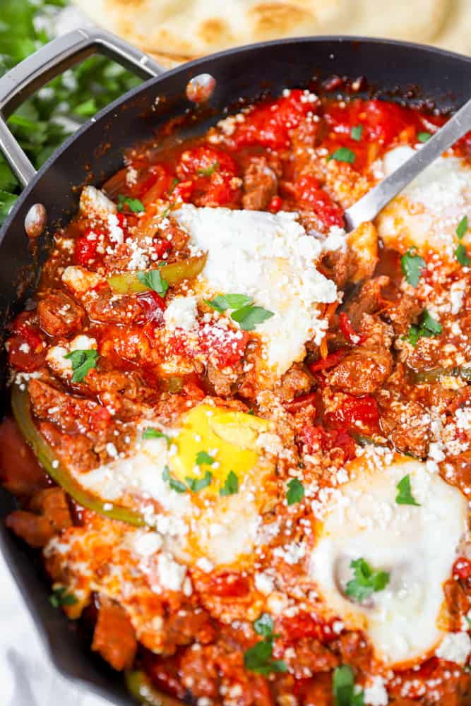 pan of shakshuka topped with eggs and a large