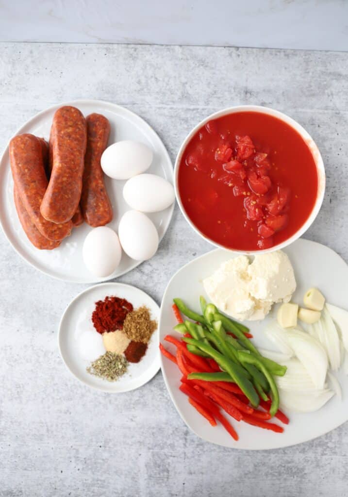 overhead shot of the ingredients: chorizo, eggs, peeled plum tomatoes, spice mix, queso fresco, garlic, white onions, red and green peppers.