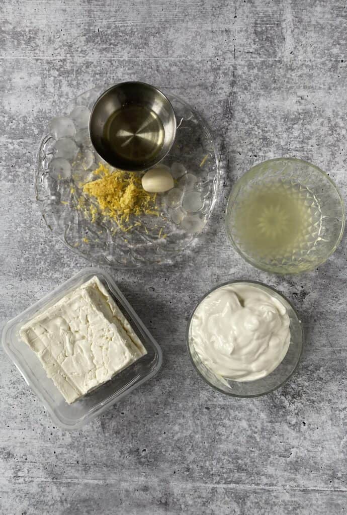 overhead shot of the ingredients: feta cheese, lemon zest, lemon juice, garlic clove, olive oil, sour cream.