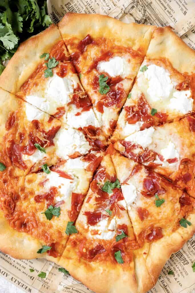 overhead shot of the vodka sauce pizza with parsley on beige newsprint paper.