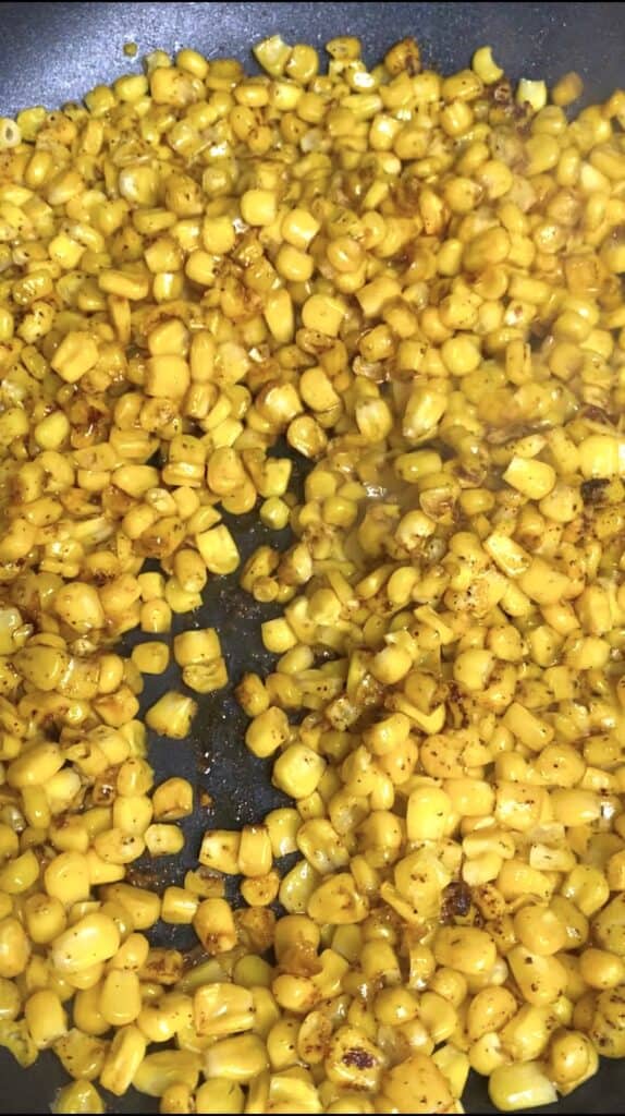 showing the seasoned corn being cooked in the pan.